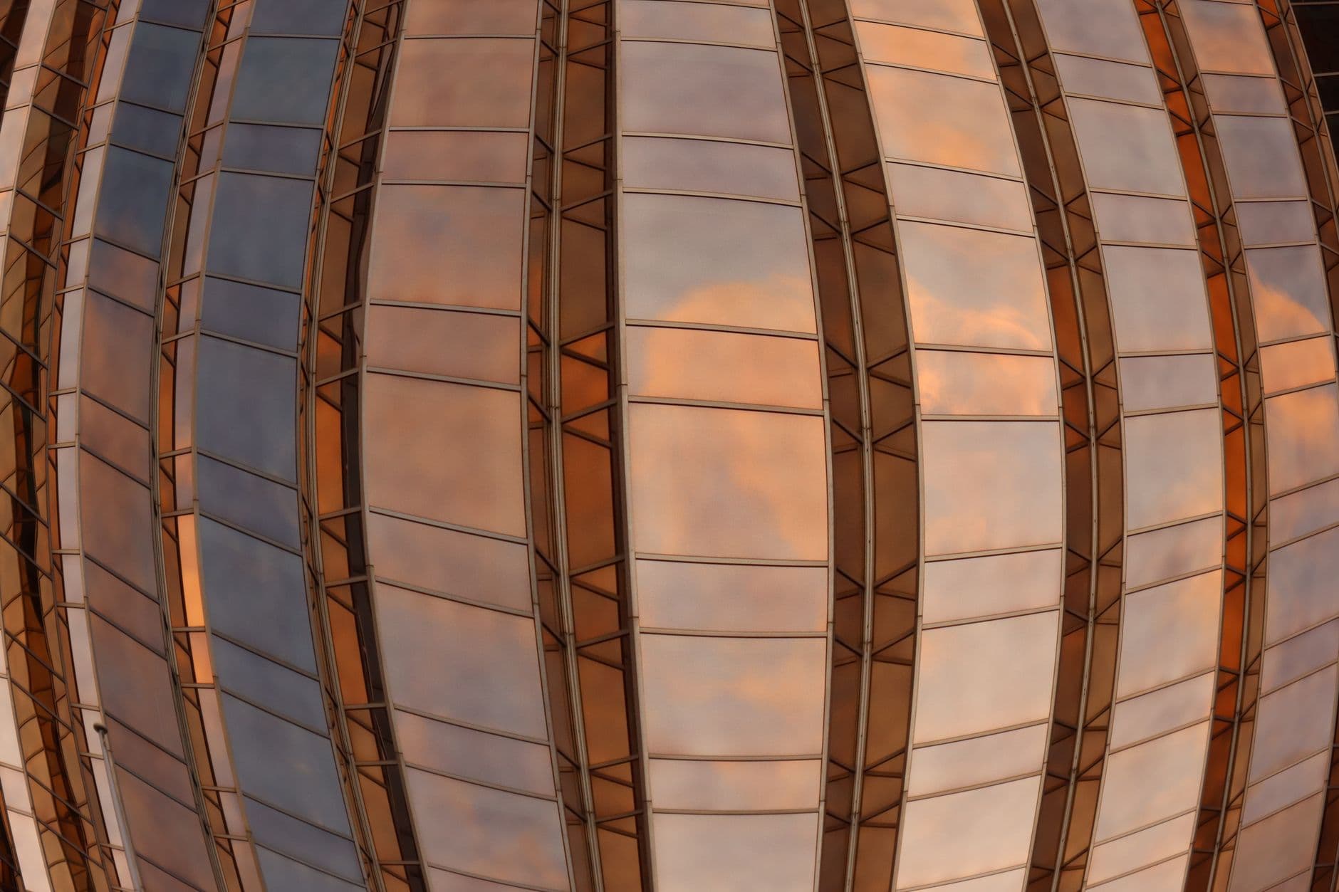 Futuristic glass dome in Melbourne reflecting a colorful sky.