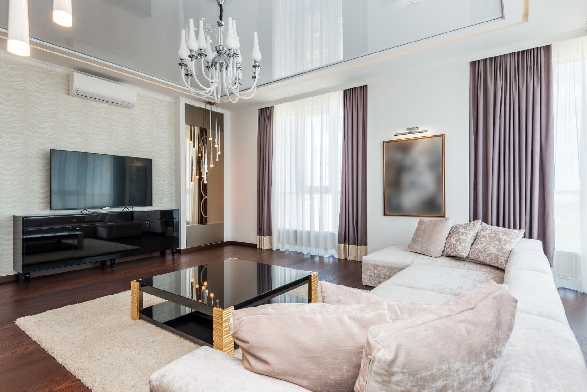 A sophisticated modern living room featuring a chandelier, plush furniture, and elegant decor.